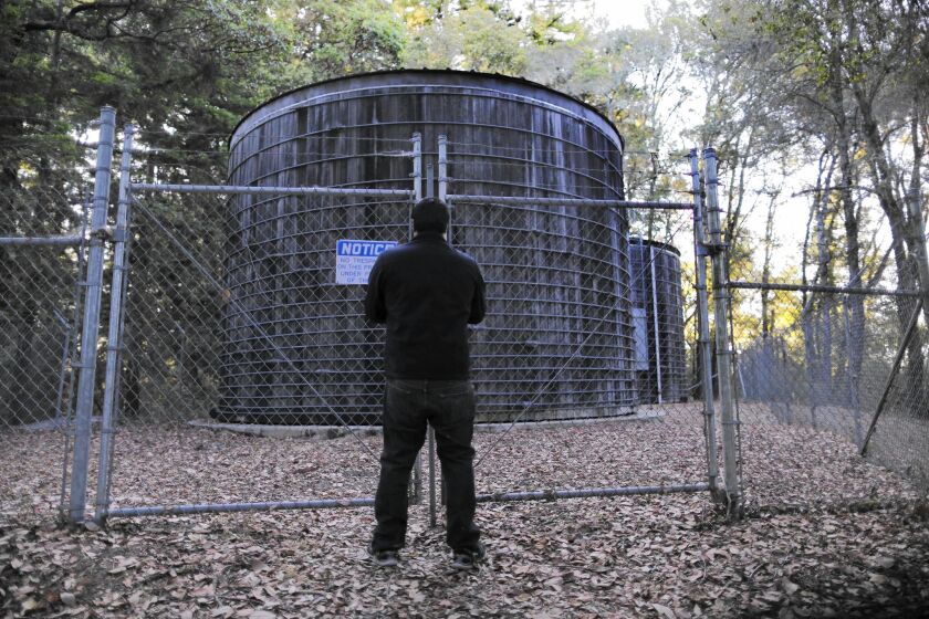 Ricardo Villa, a water district employee, locks a gate after checking redwood water tanks.