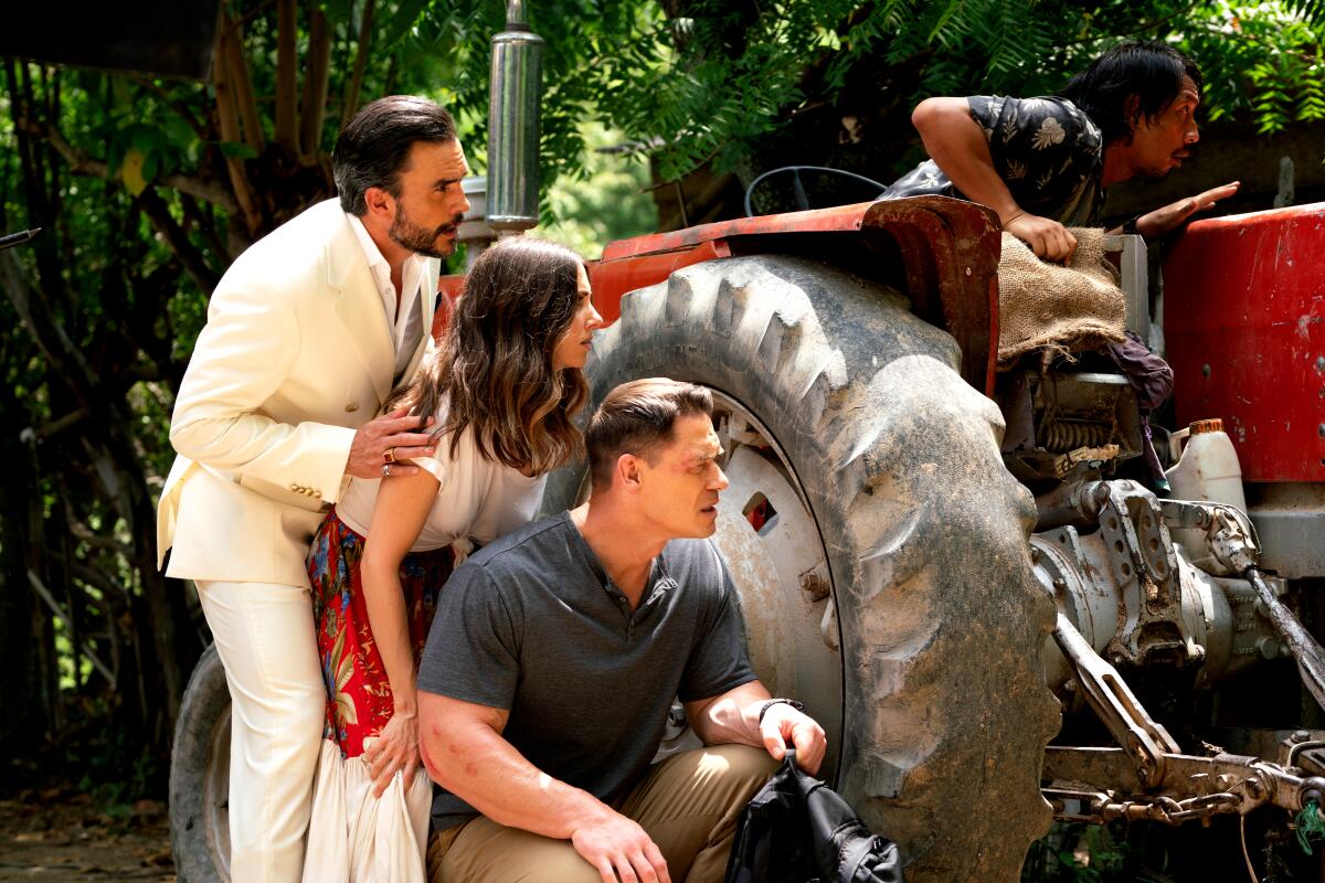 Three people crouch behind a tractor.