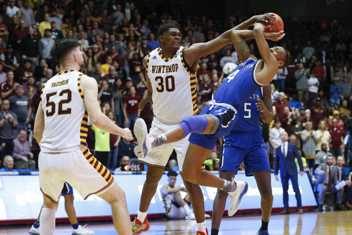 Winthrop forward D.J. Burns (30) fouls Hampton guard Greg Heckstall as Winthrop guard Chandler Vaudrin (52) looks on in the second half in the Big South tournament championship in Rock Hill, S.C. on Sunday.
