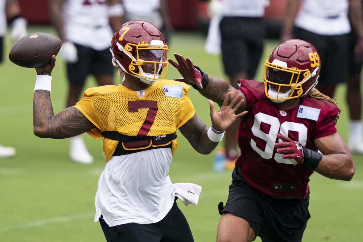 Washington quarterback Dwayne Haskins Jr. (7) passes under pressure from defensive end Chase Young (99) during an NFL football practice at FedEx Field, Monday, Aug. 31, 2020, in Washington. (AP Photo/Alex Brandon)