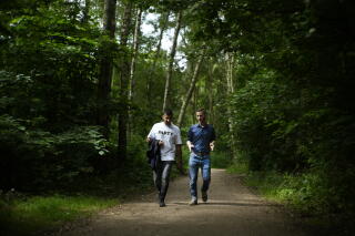 two men walk in a wooded park