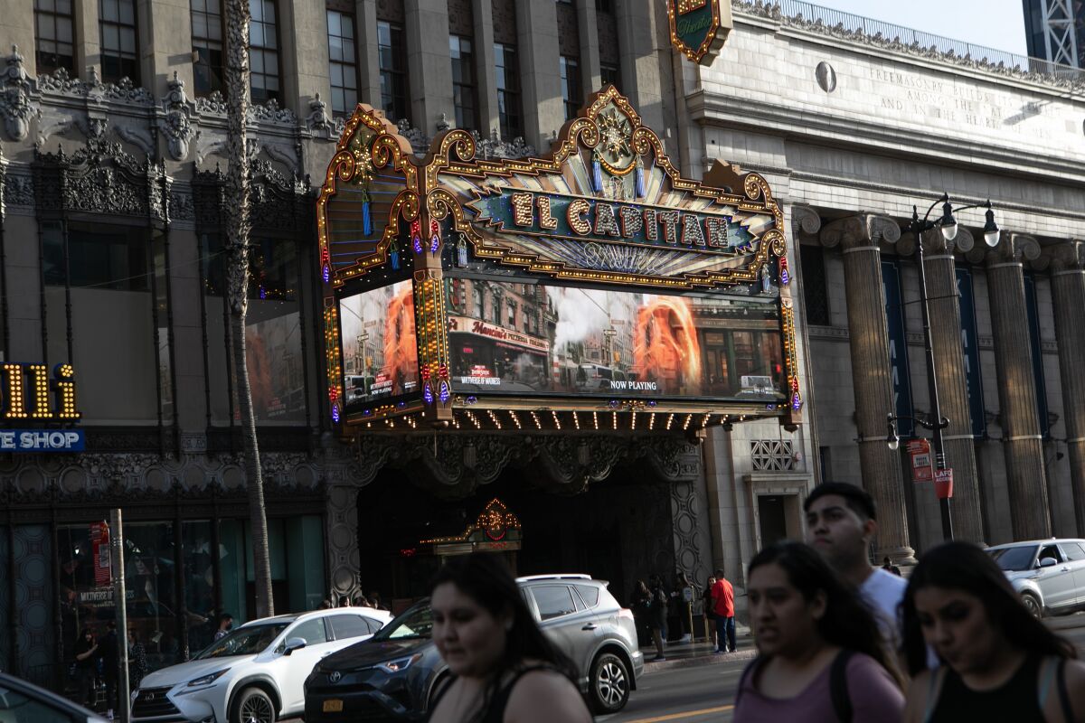 People walk in front a lit-up marquee.