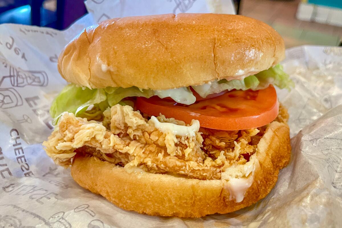 A spicy chicken burger with lettuce and tomato in a bun.