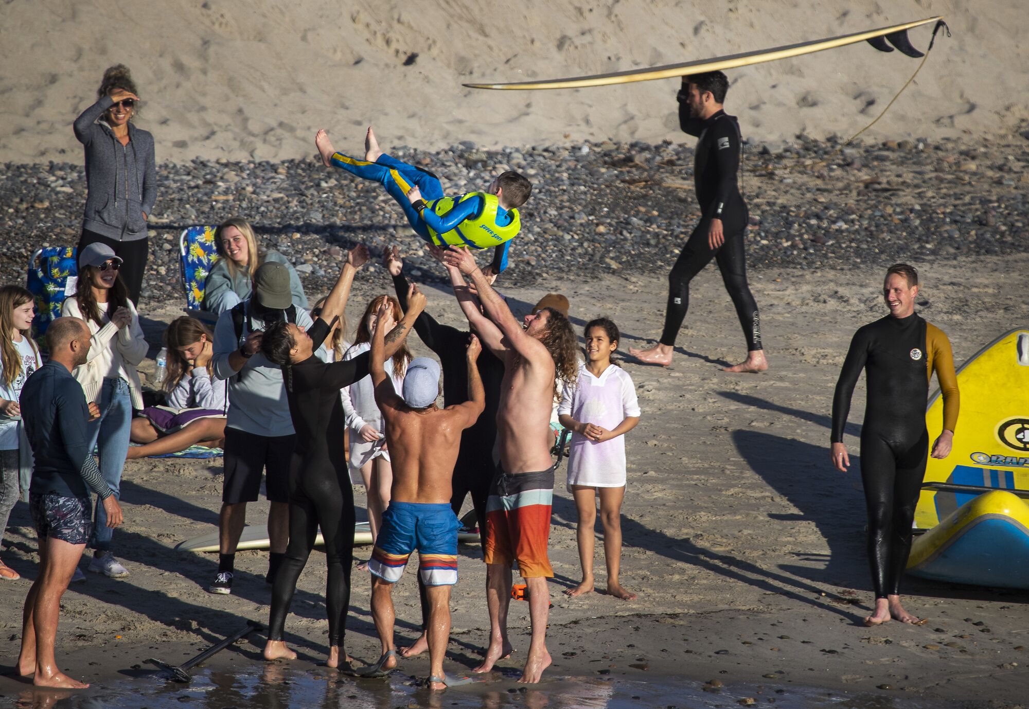 Surfers toss Cohen Schuller into the air.