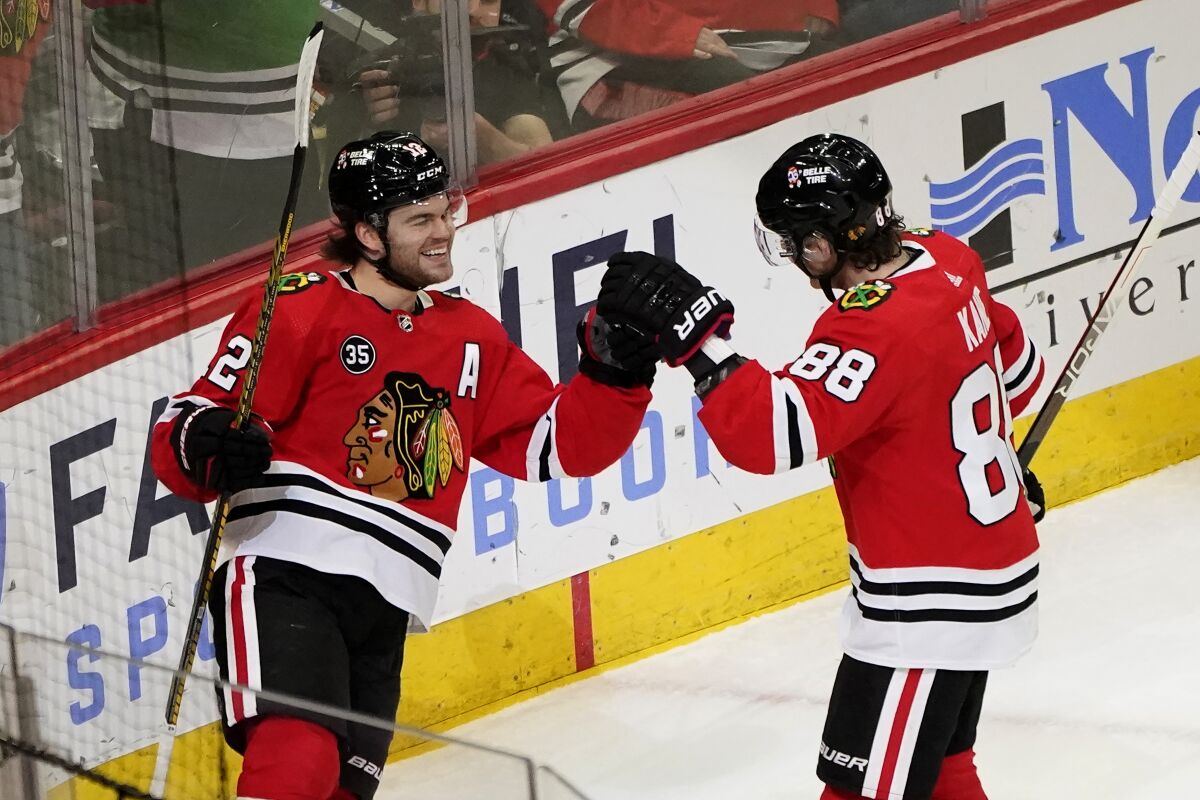 Chicago Blackhawks' Alex DeBrincat (12) celebrates his goal with Patrick Kane during the first period of an NHL hockey game against the Anaheim Ducks Tuesday, March 8, 2022, in Chicago. (AP Photo/Charles Rex Arbogast)
