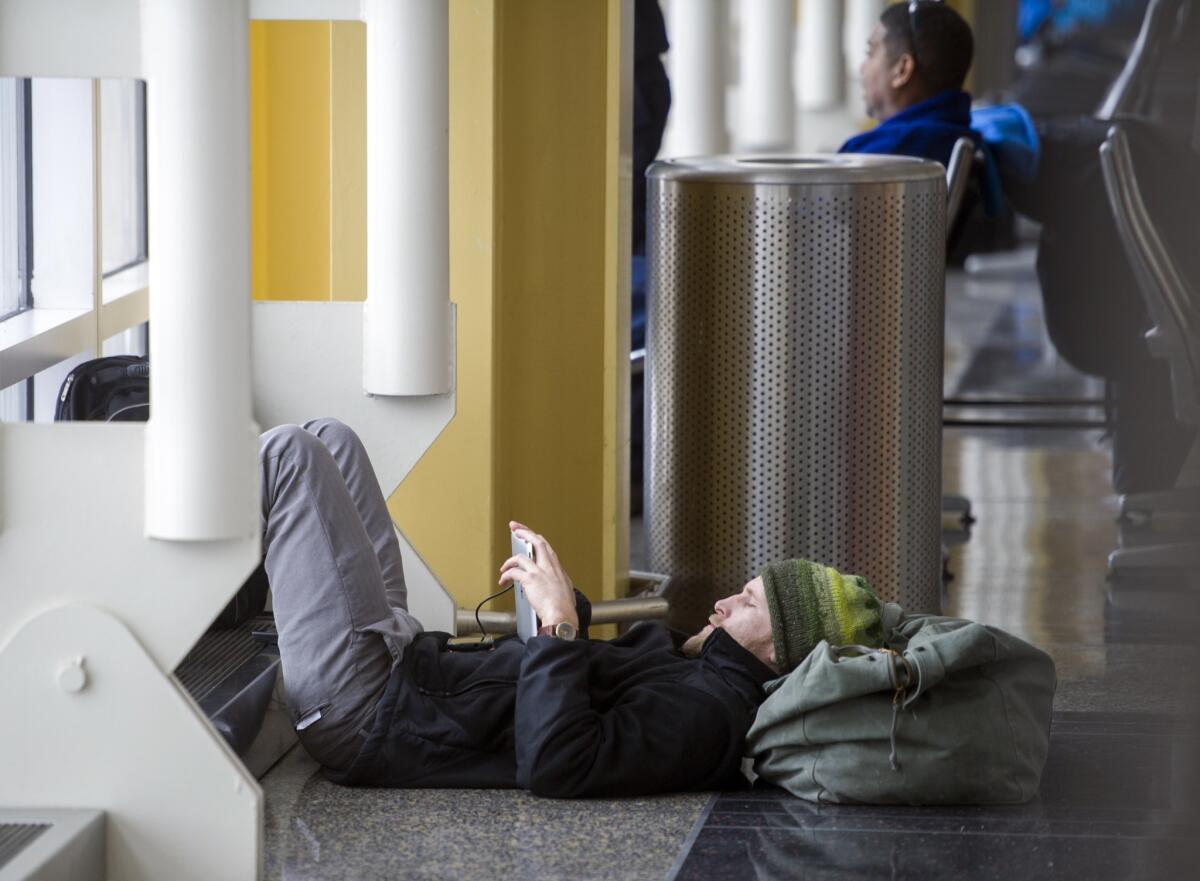 After spending the night at the airport, Ernie Harmon, 27, of Long Island, N.Y., watches a movie while waiting for a flight to California on Thursday at Washington's Ronald Reagan National Airport.
