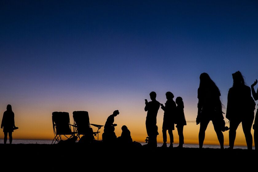 Beachgoers are cast in silhouette after the last rays of sunlight escape into the night on Santa Monica Beach on Wednesday.