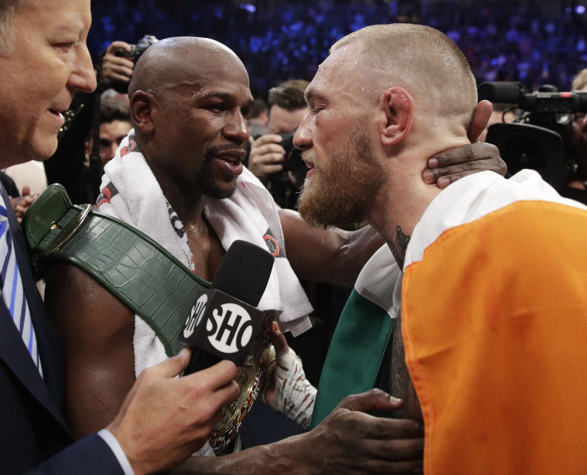 Floyd Mayweather Jr. embraces Conor McGregor after their super-welterweight fight.