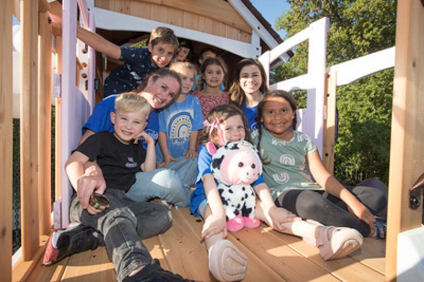 Lizzie Grant, center front, poses at the reveal party for a play structure she can share with her human and animal friends. 