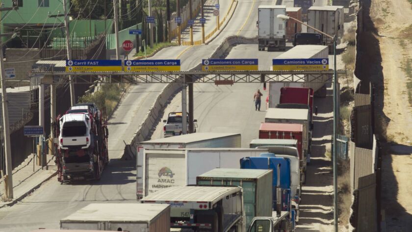 Trucks line up Friday by the U.S. border fence in Tijuana to cross to the United States at Otay Mesa.
