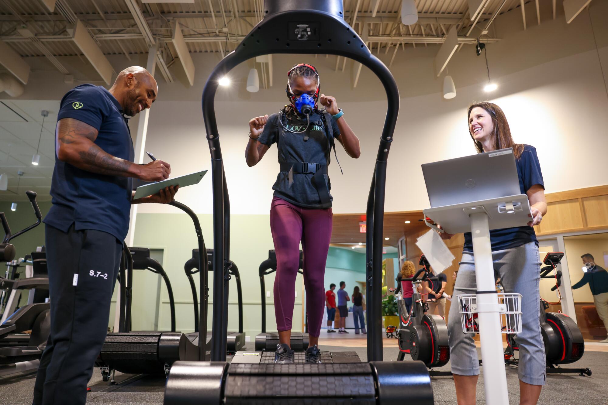 A woman training on a treadmill while wearing an oxygen mask.