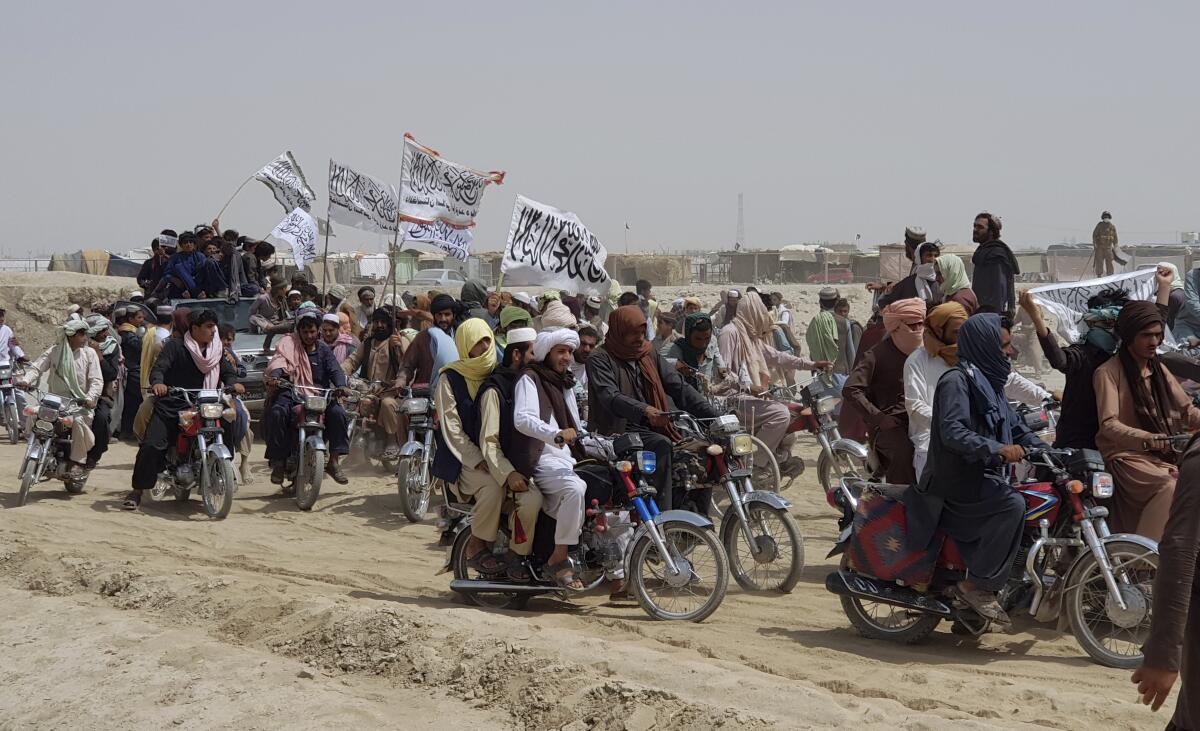 A truck carrying men joins many others riding on motorcycles, some carrying white flags with Arabic script
