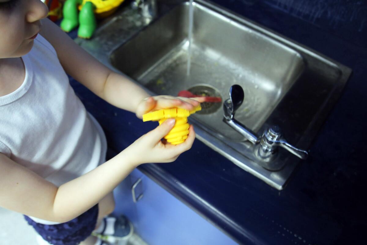 Aubree Casas, 5, uses a ScrubBee to wash her hands during class at Bret Harte Elementary School in Burbank.