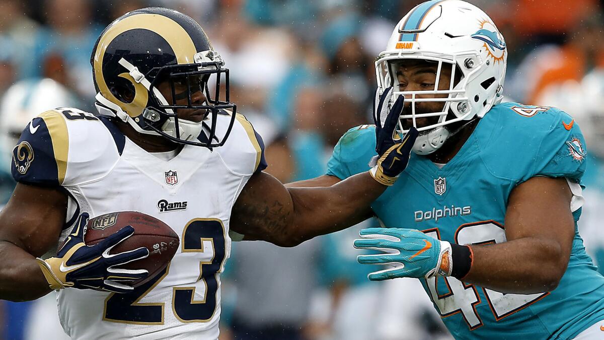 Dolphins linebacker Spencer Paysinger holds Rams running back to a short gain during a game last season at the Coliseum.