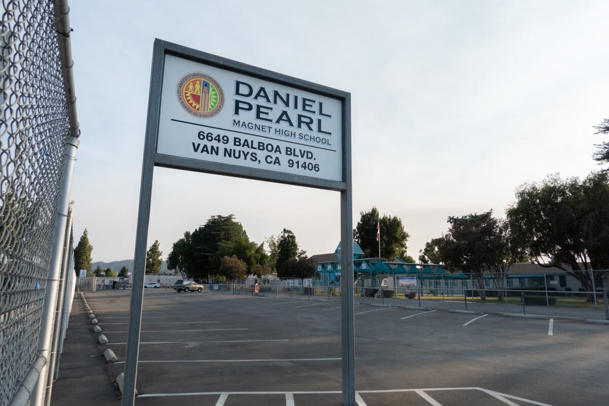 A sign for Daniel Pearl Magnet High School in a parking lot.