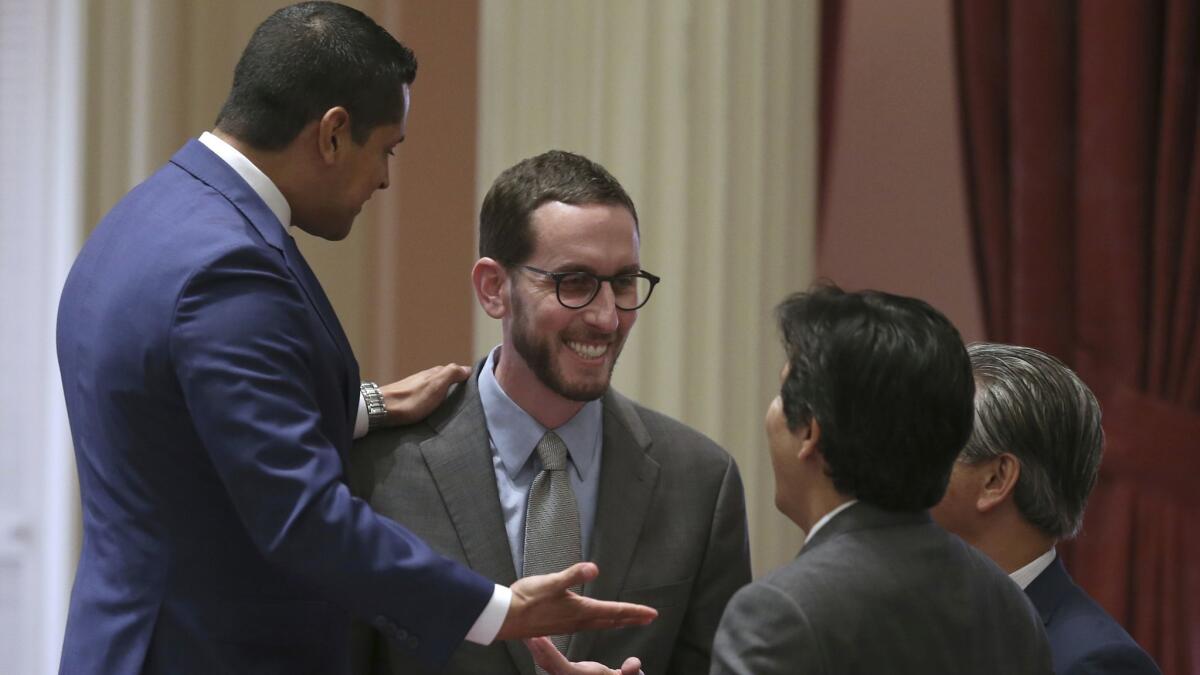 Assemblyman Miguel Santiago (D-Los Angeles), left, stands on a chair as he celebrates the passage of the net neutrality bill he co-wrote with state Sen. Scott Wiener (D-San Francisco), second from left.