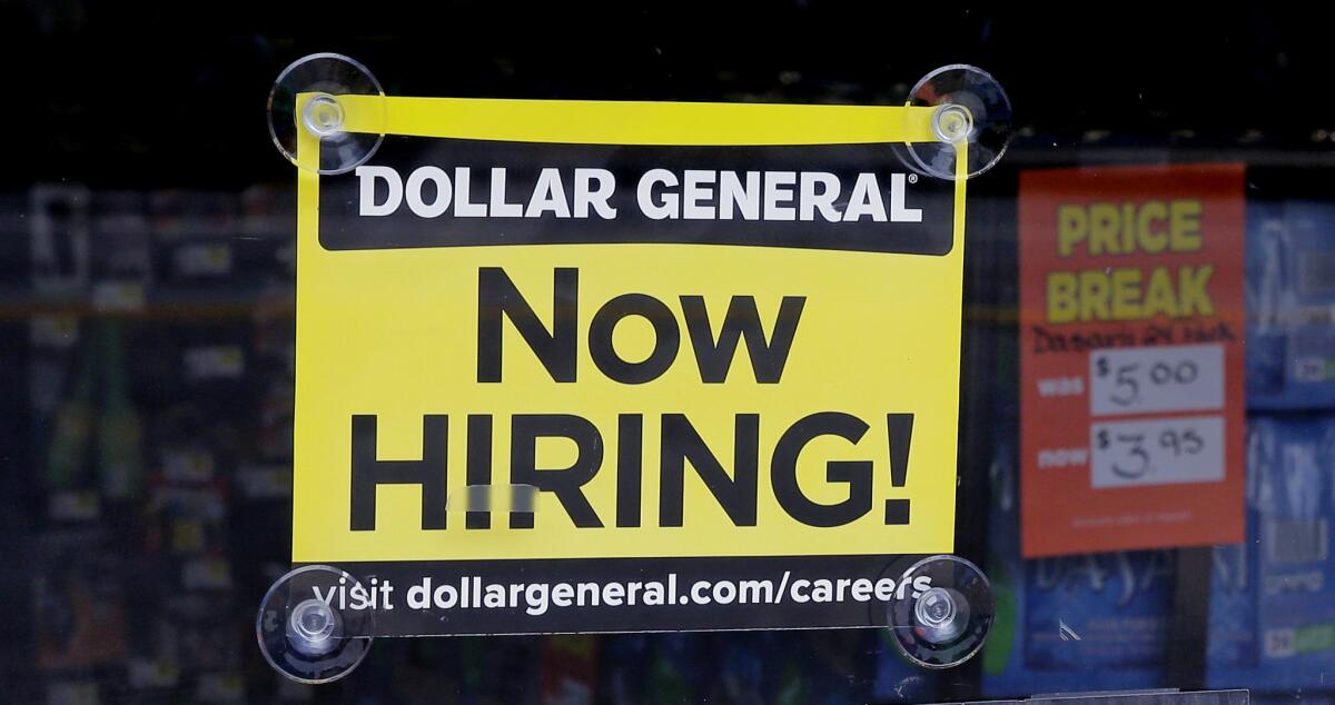 A "Now Hiring" sign hangs in the window of a Dollar General store in Methuen, Mass., in May.