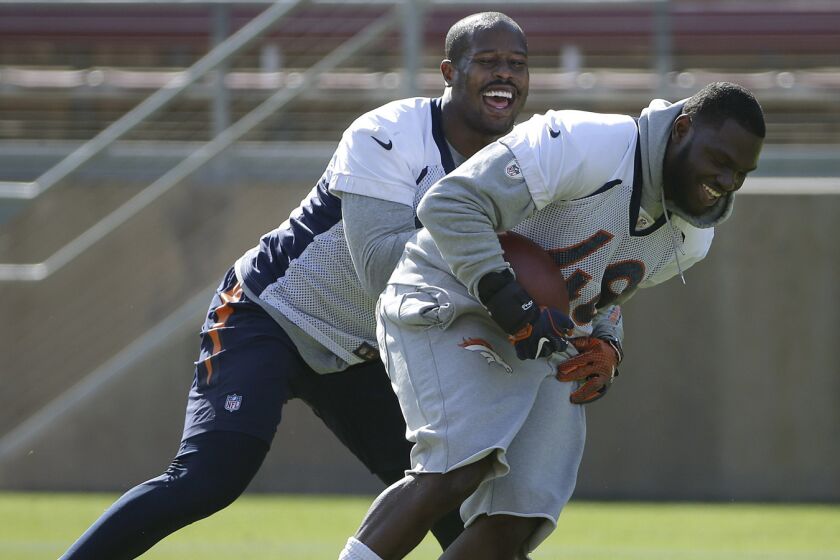Denver Broncos linebacker Von Miller, left, laughs as he grabs linebacker Shaquil Barrett during a drill at an NFL football practice/