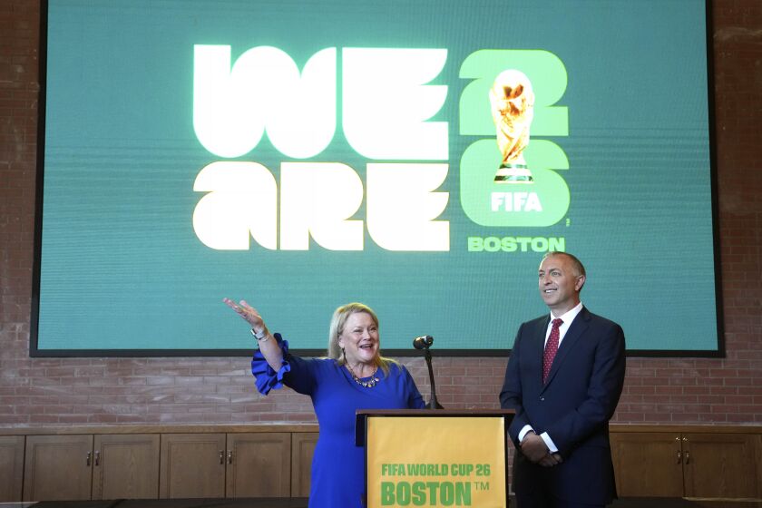 Martha J. Sheridan, prseidenta y directora general de Meet Boston, a la izquierda, y Brian Bilello, presidente de Boston Soccer 2026, y del Revolution de Nueva Inglaterra, permanecen delante de un logotipo proyectado en una pantalla como parte de la marca local con motivo de los partidos de la Copa del Mundo 2026 que tendrán lugar en la ciudad, durante una ceremonia en Boston, el jueves 18 de mayo de 2023. (AP Foto/Steven Senne)