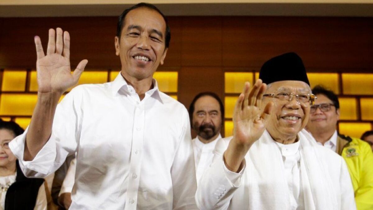 Indonesian President Joko Widodo, left, and his running mate, Ma'ruf Amin, wave at a news conference in Jakarta after polls closed in the April 17 election.