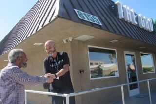 Ali Benson (left) shakes hands with Sean McDermott, the owner of La Mesa’s lone medical marijuana dispensary, The Grove, in a photo taken last year. The city has clarified language in its Municipal Code so that people with a state-issued ID card will not be charged tax while those without the card will have to pay an additional 4 percent tax.