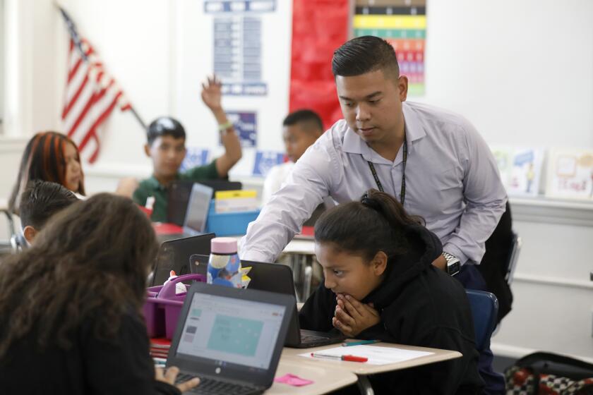 LONG BEACH, CALIF. -- WEDNESDAY, OCTOBER 30, 2019: Learning Director Eric Cabacungan, helps sixth-grad student Melanie Ortiz, 11, during a Math Sixth development class at Stephens Middle School in Long Beach, Calif., on Oct. 30, 2019. Stephens Middle School is using a "growth" measure to track which students are making faster gains academically and to determine why. (Gary Coronado / Los Angeles Times)