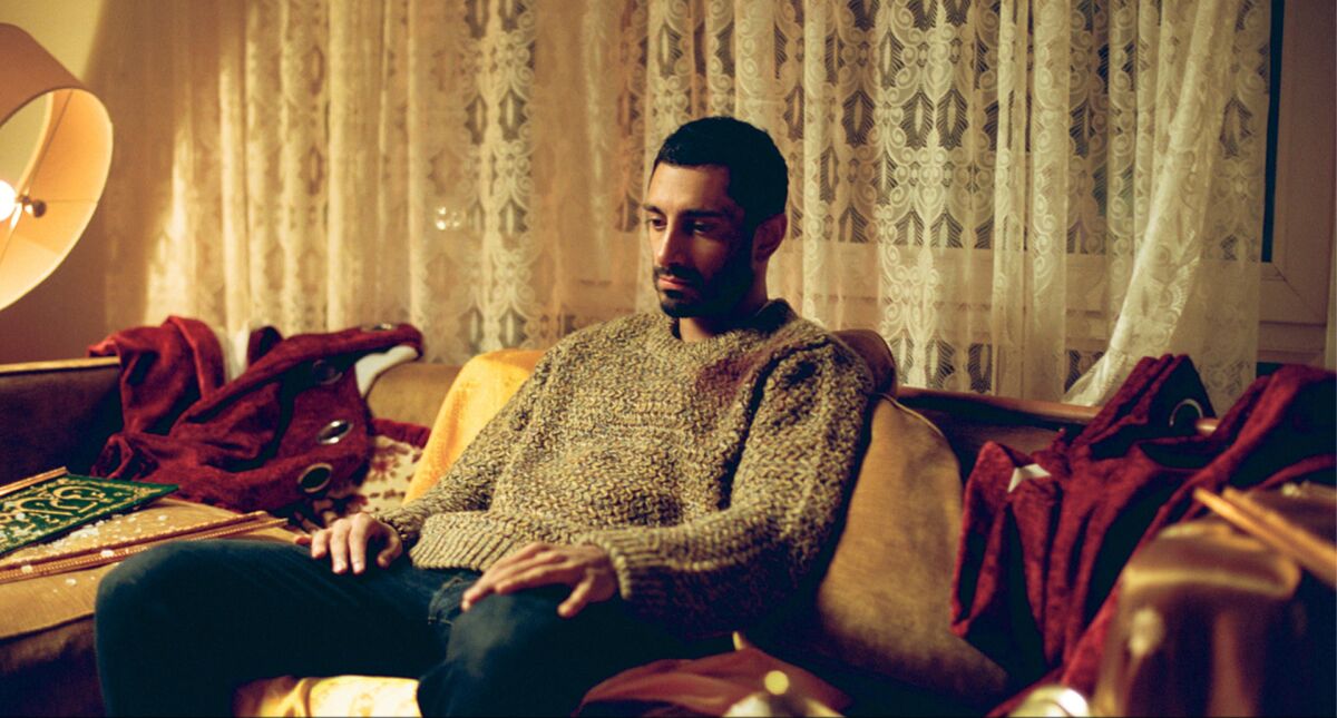 A man sits on a sofa with his hands on his knees