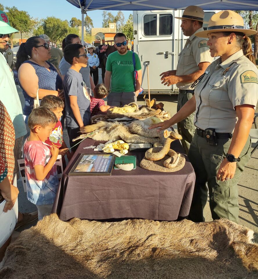 County of San Diego Parks and Recreation Department Park Ranger Alicia Watkins and Supervising Park Ranger David Moniz, right, talk with National Night Out attendees.