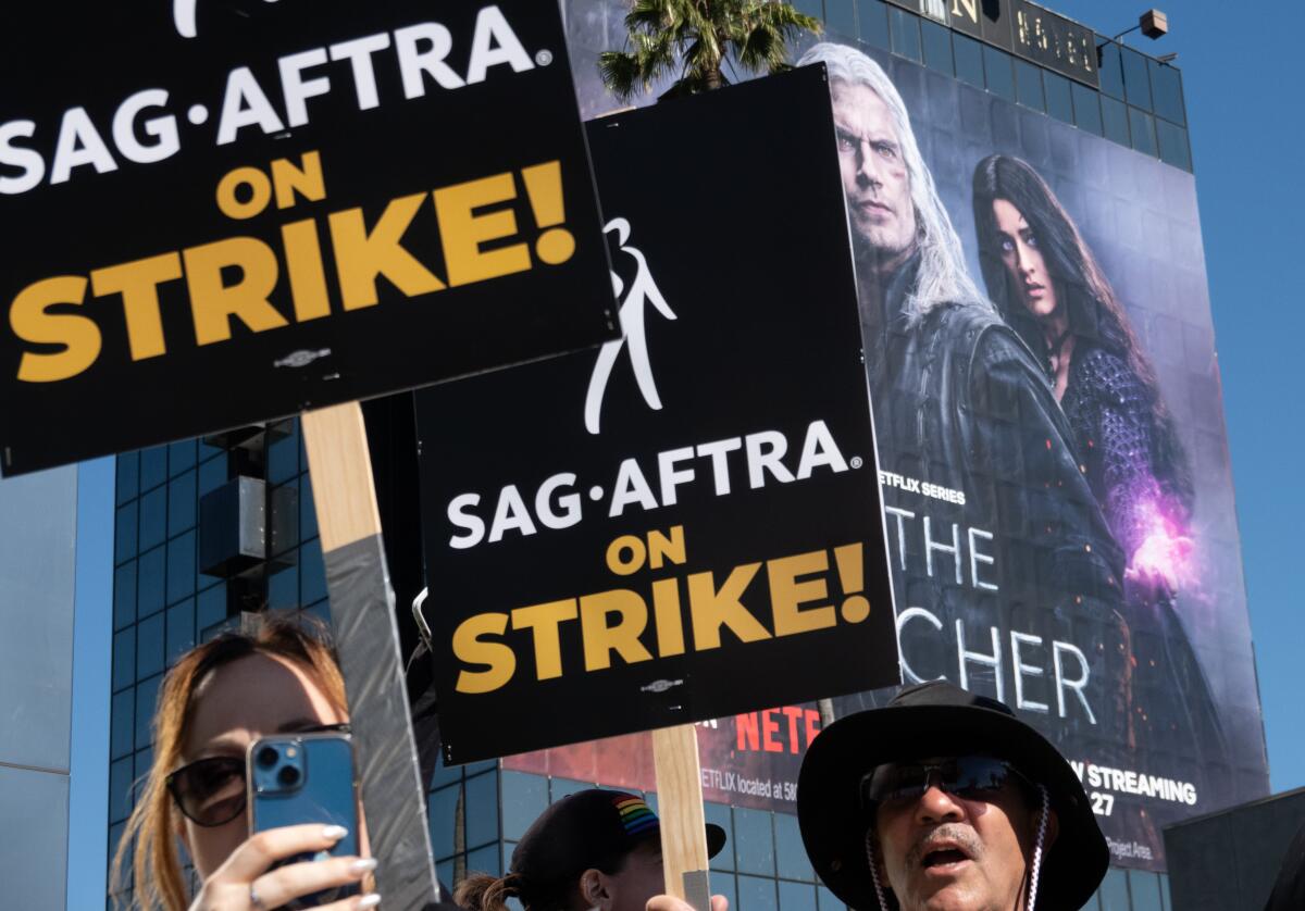 People hold signs reading "SAG-AFTRA on strike!"