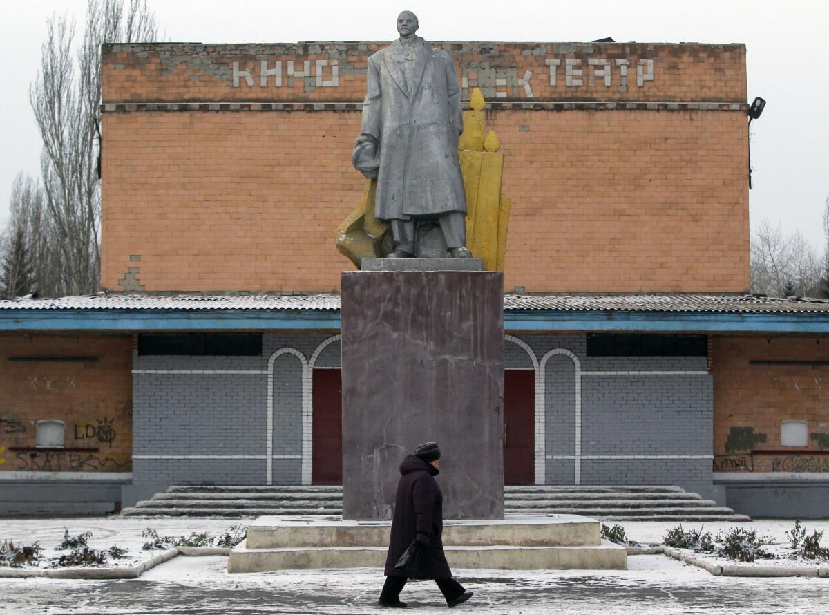 A woman passes by a statue of Vladimir Lenin in the central square of Ukrainsk, a town in in eastern Ukraine.