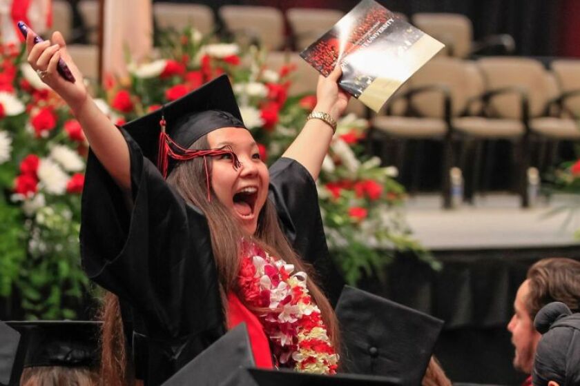 Noelle Green waves to family and friends before College of Arts and Letters graduation at SDSU