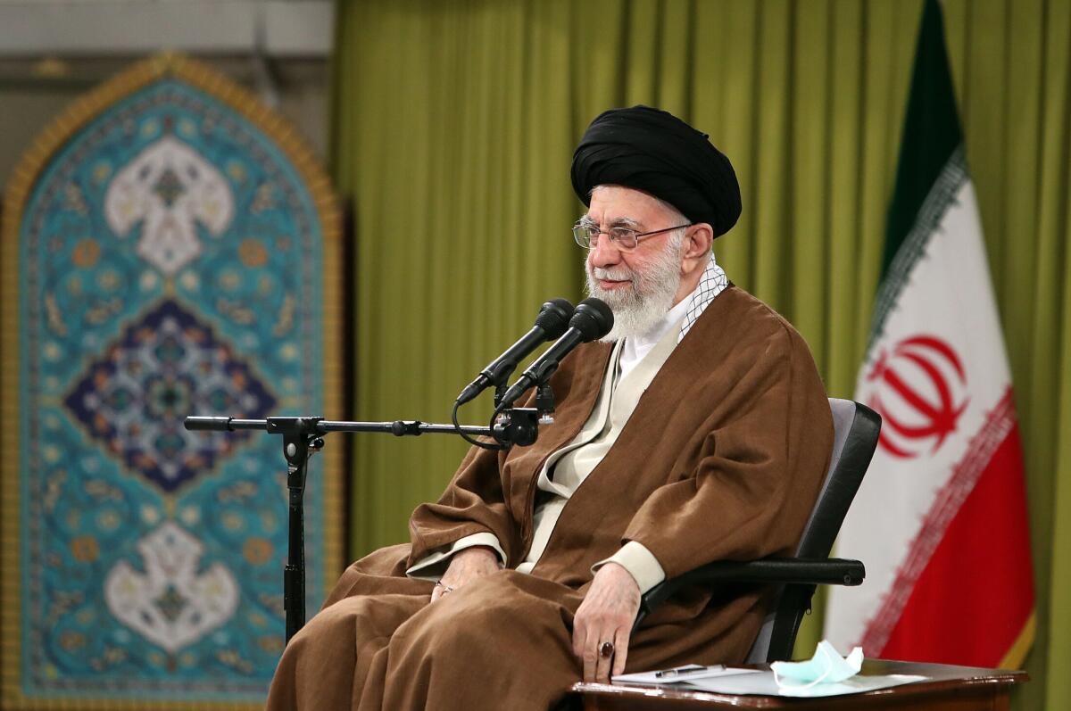 Iranian Supreme Leader Ayatollah Ali Khamenei seated before microphones