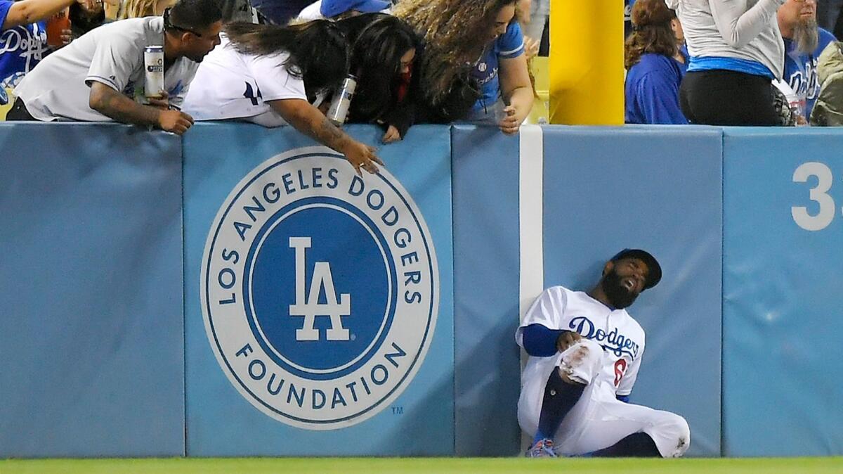 Dodgers left fielder Andrew Toles writhes in pain after injuring his right knee while trying to catch a ball hit for a ground-rule-double on May 9.
