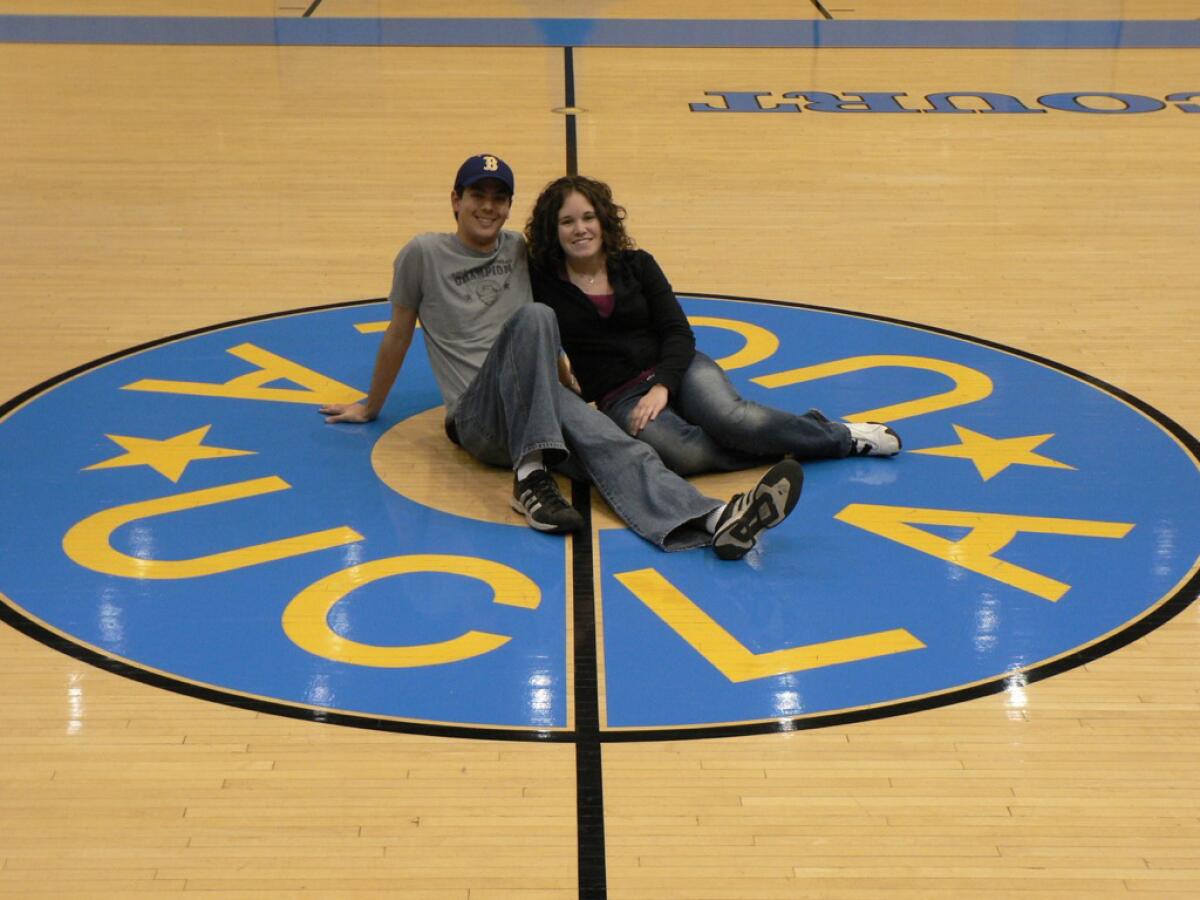 A man and a woman sit together on the court at Pauley Pavilion