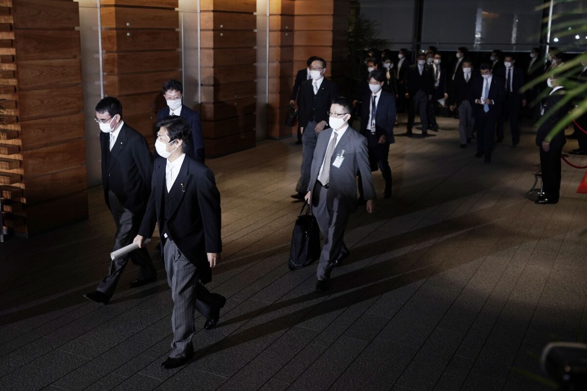 Newly appointed ministers, left, are escorted by staffs as they leave the official residence for the Imperial Palace to attend the attestation ceremony of the new cabinet by Prime Minister-elect Yoshihide Suga, Wednesday, Sept. 16, 2020, in Tokyo. (AP Photo/Eugene Hoshiko)