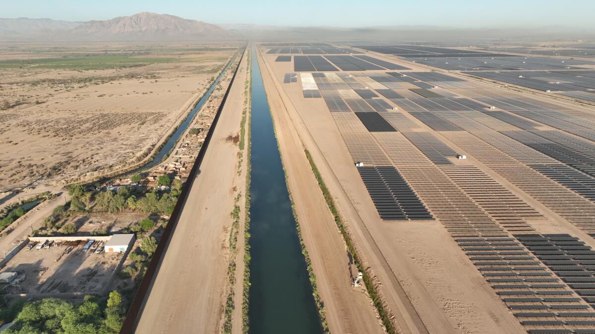 Solar farms line one side of river in an aerial image.