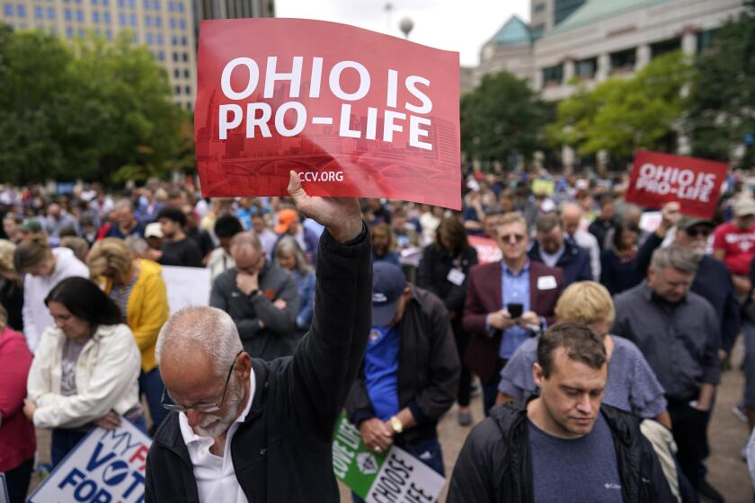 FILE - Paul Meacham holds high a sign that reads "Ohio is pro-life" as the crowd prays during the Ohio March for Life rally at the Ohio State House in Columbus, Ohio, Friday, Oct. 6, 2023. Abortion questions are already on the ballot for 2024 in two states and could also appear in several others. (AP Photo/Carolyn Kaster)