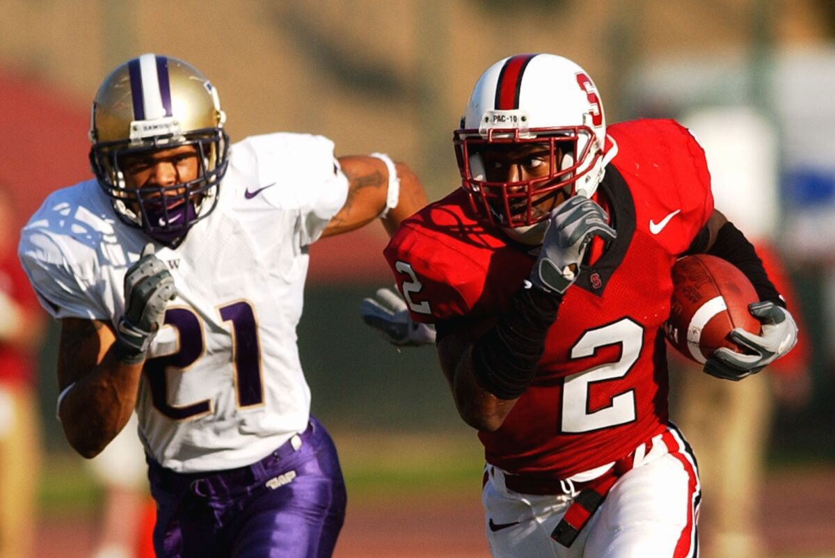 A football player on the right is returning an interception while another player chases him.