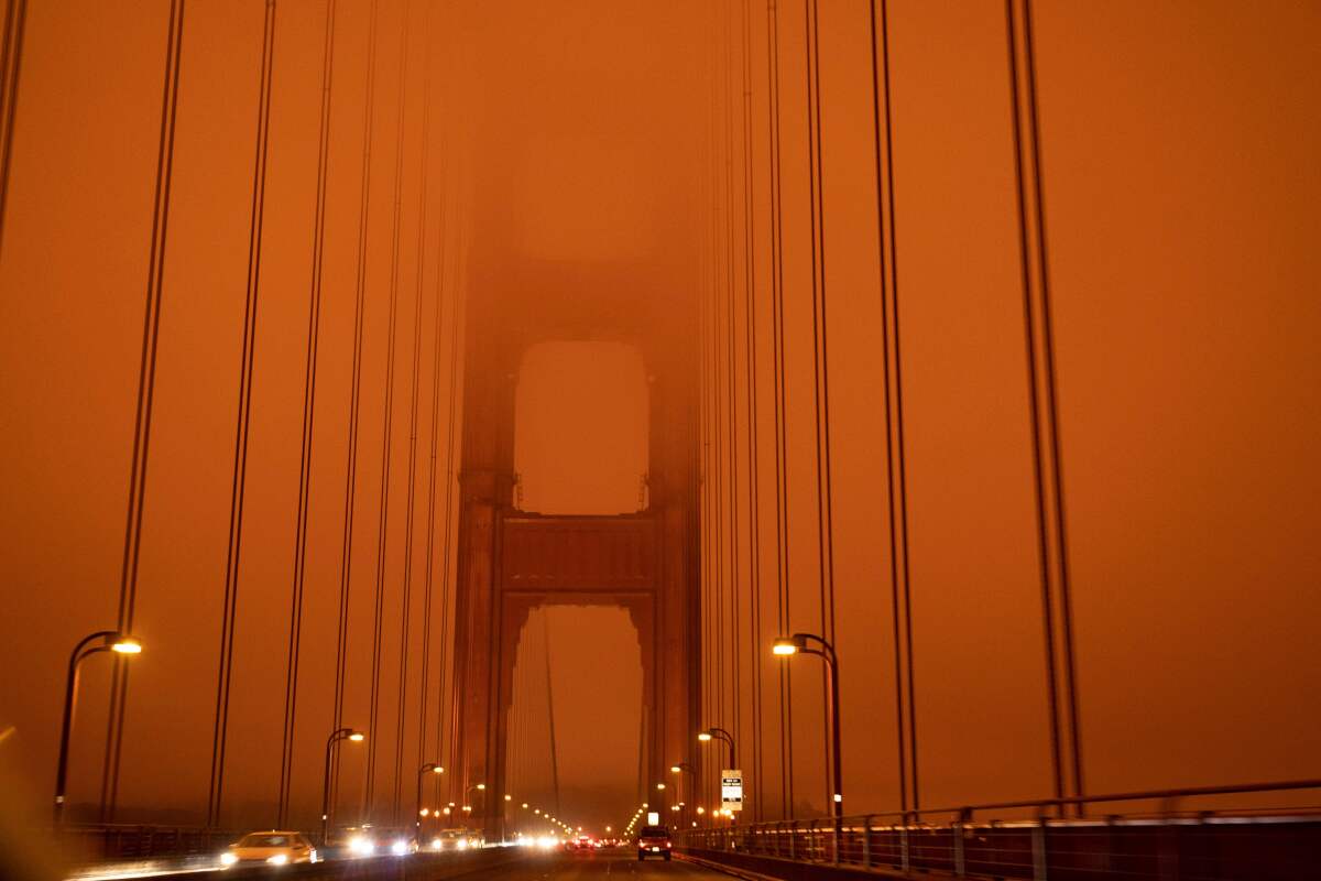 The Golden Gate Bridge in San Francisco is clouded in wildfire smoke with an orange sky