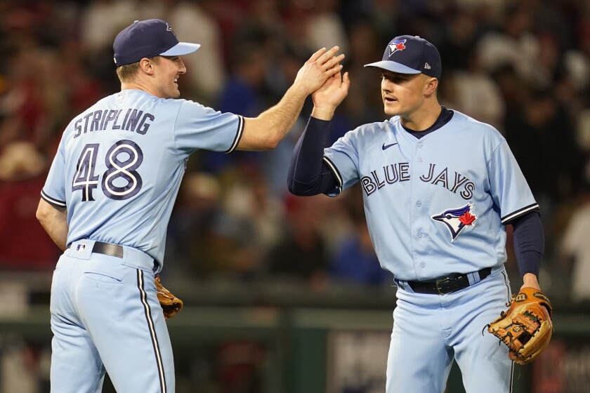 Toronto Blue Jays relief pitcher Ross Stripling, left, high-fives third baseman Matt Chapman.