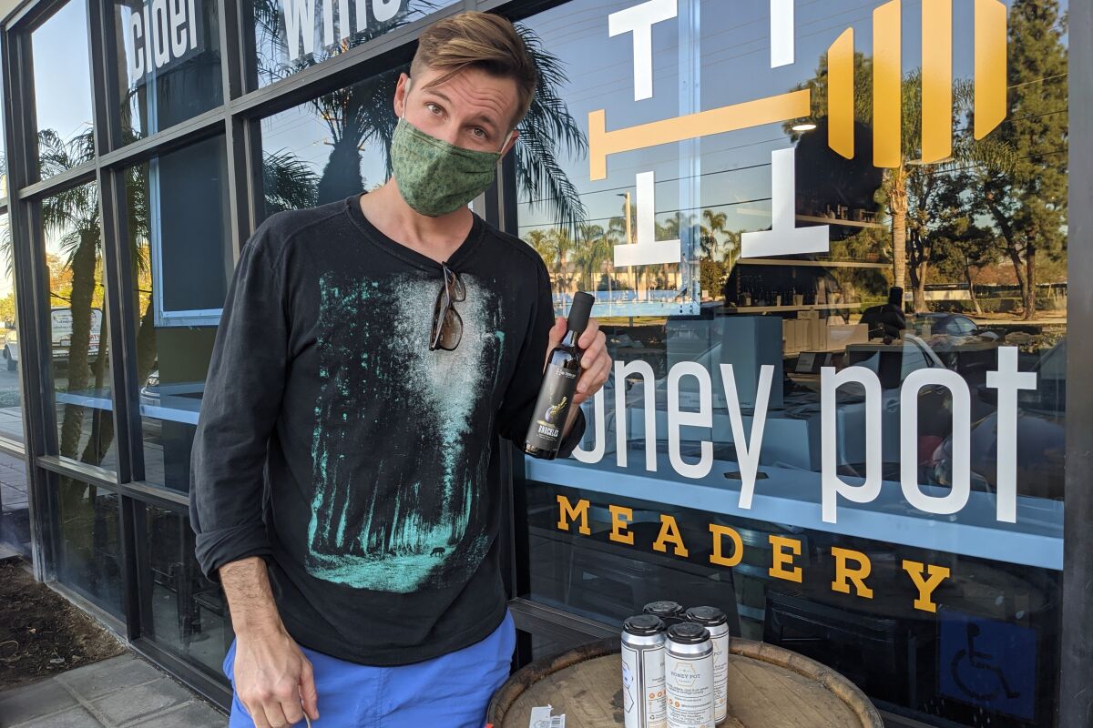 A person next to a Honeypot Meadery sign