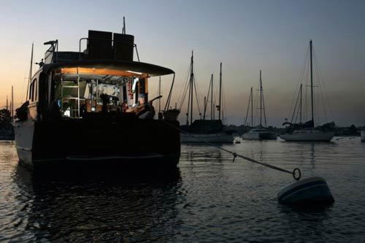 Dave Dixon's 37-foot mahogany boat is moored in Newport Harbor near the Balboa Pavilion. Dixon lives on the boat that he bought with a credit card for $10,000, plays golf and tennis regularly and supports his lifestyle on $565 a month.