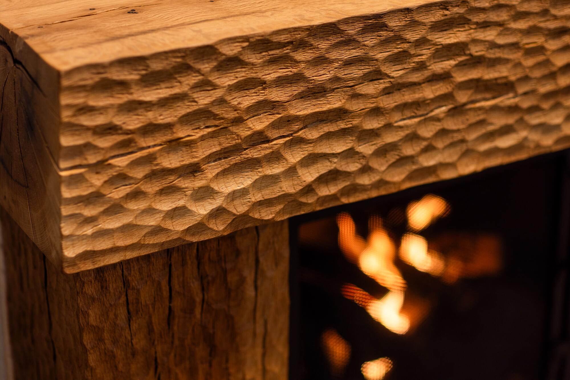 Chisel marks create a pattern on a wood fireplace mantel