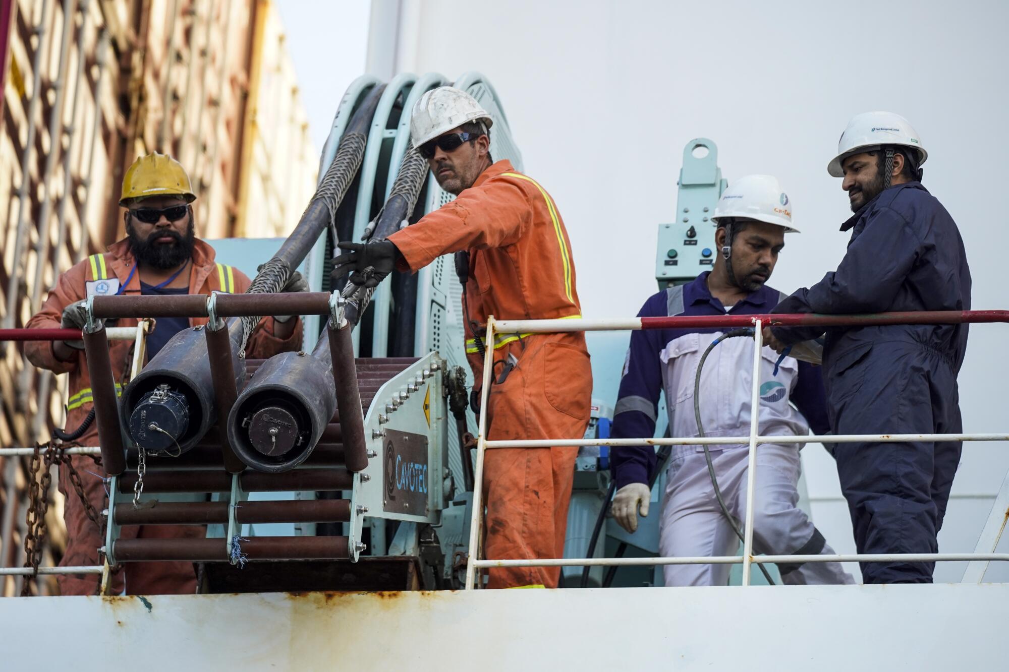 Power cables are lowered from the container ship YM Movement so longshoremen in Wilmington can connect it to the power grid.