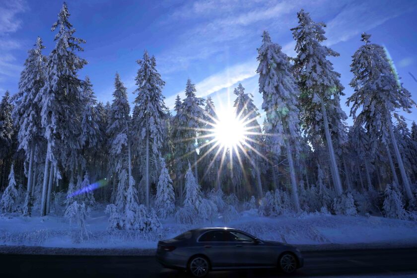 A car passes by snow covered trees in Oberhof, Germany, Wednesday, Jan. 25, 2023. (AP Photo/Matthias Schrader)
