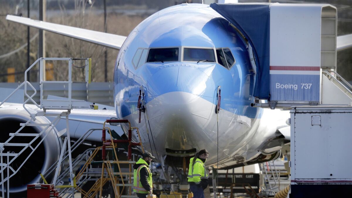 Workers walk past a 737 Max 8 airplane being built at Boeing Co.’s assembly plant in Renton, Wash.