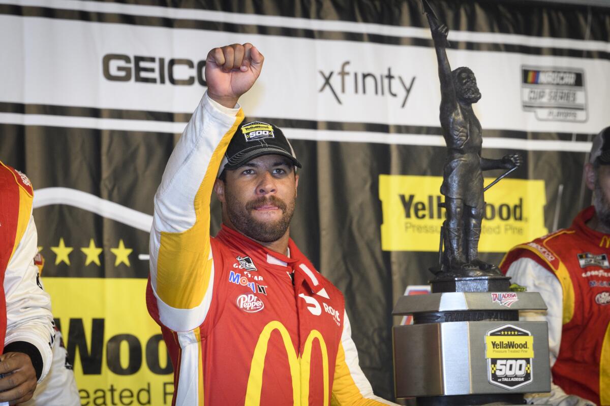 Bubba Wallace celebrates next to the trophy after winning a NASCAR Cup.