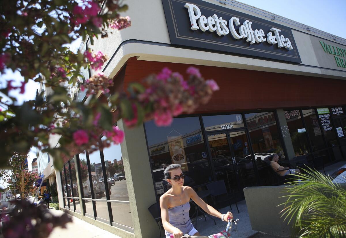 A woman rides a bike past a Peet's Coffee & Tea outlet in Tarzana on July 23, 2012