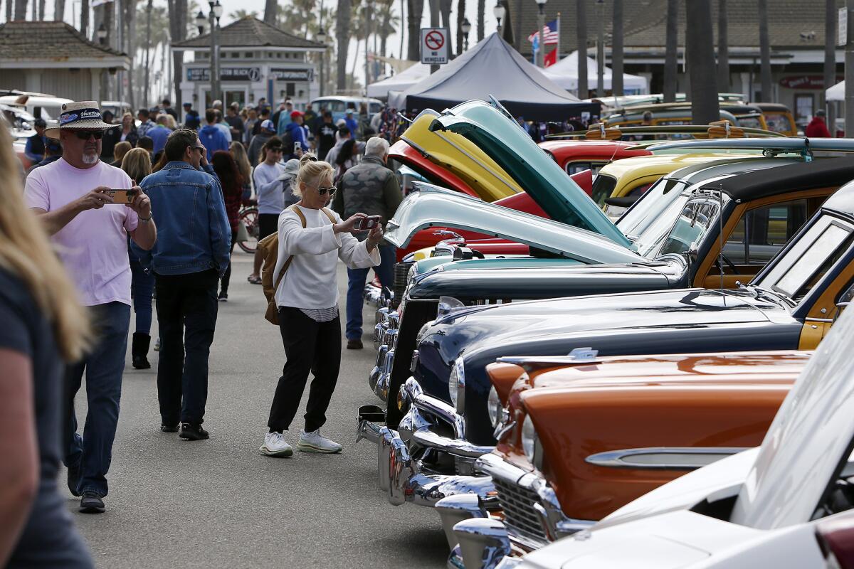 Visitors take pictures of classic cars during the 20th annual Beach Cruisers event on Saturday in Huntington Beach.