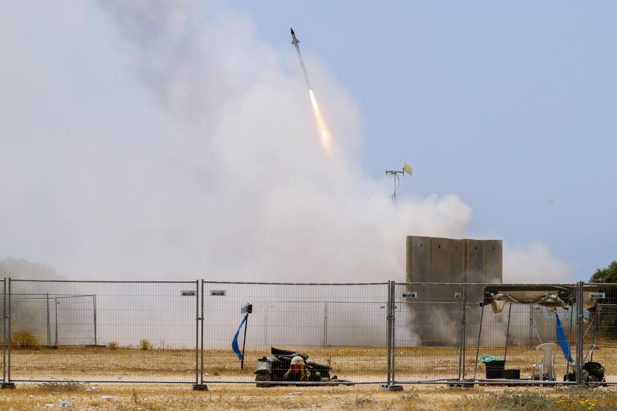 FILE - A Israeli soldier takes cover as an Iron Dome air defense system launches to intercept a rocket from the Gaza Strip, in Ashkelon, southern Israel, on May 11, 2021. Israel’s prime minister on Tuesday, Feb. 1, 2022, acknowledged that its Iron Dome defense system is too expensive and the country is speeding the rollout of laser technology to protect it from rocket attacks. Naftali Bennett told a security conference that the new generation of technology -- a “laser wall” -- will be unveiled within a year in southern Israel. (AP Photo/Ariel Schalit, File)